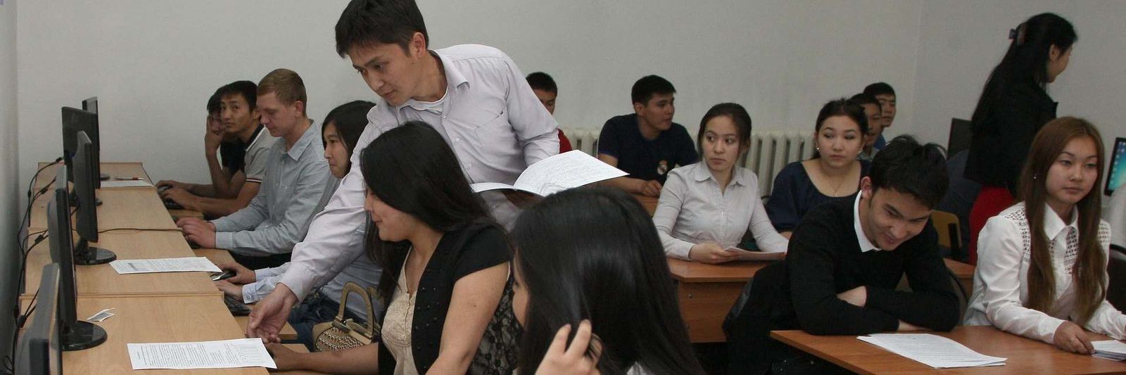 Занятие в компьютерном классе: преподаватель помогает студентам с заданием
