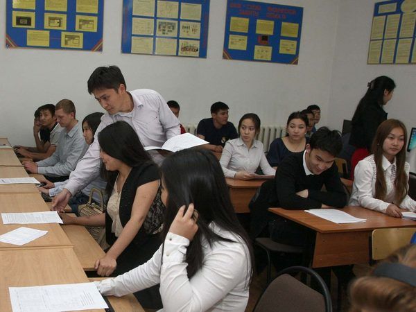 Занятие в компьютерном классе: преподаватель помогает студентам с заданием.